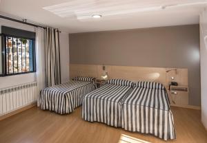 Un dormitorio con dos camas y una ventana. en Hotel Puerta de la Santa, en Ávila