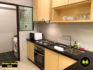 a kitchen with a stove and a sink and a microwave at Luco Apartments @ Imperial Suites Kuching in Kuching