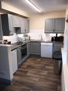 a kitchen with gray cabinets and white appliances at The Flat Axbridge in Axbridge