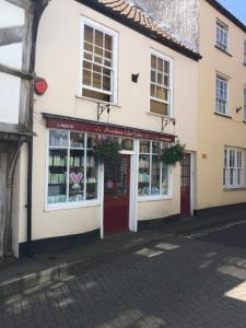 un magasin avec une porte rouge dans une rue dans l'établissement The Flat Axbridge, à Axbridge