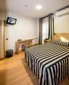 um quarto de hotel com uma cama listrada a preto e branco em Hotel Puerta de la Santa em Ávila