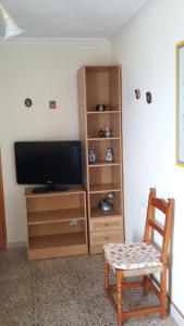 a room with a tv and a chair and a cabinet at Apartamento Venecia in Águilas