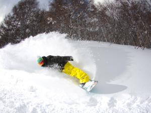 a person is laying in the snow on a snowboard at Urabandai Lake Resort in Kitashiobara