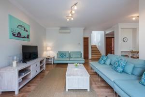 a living room with a blue couch and a tv at Cottesloe Sea Salt Abode in Perth