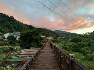 a wooden bridge over a river with a sunset at Mountain Lodge Hostel in Nanzhuang