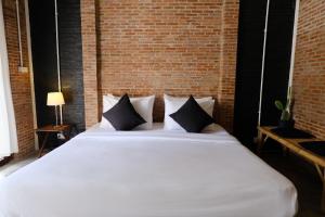 a large white bed in a room with a brick wall at Samatha Bed & Breakfast in Ko Tao