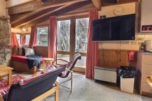 sala de estar con sofá y TV en una habitación en Bindi - Alpine Getaways's Chalet at Tower Rd en Dinner Plain