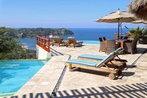 a pool with chairs and an umbrella next to the ocean at Villas Piedra Blanca in Sayulita