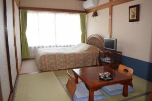 Dormitorio pequeño con cama, mesa y mesa en Pension Surf Rider, en Nishiizu