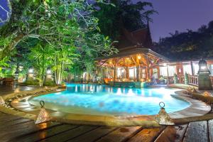 a swimming pool in front of a house at night at Sawasdee Village in Kata Beach