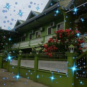 a green house with christmas lights on it at Magdalene Apartment in Balamban
