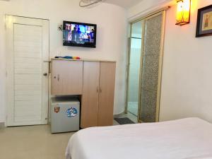 - une chambre avec un lit et une télévision murale dans l'établissement Baoanh Hostel, à Hô-Chi-Minh-Ville