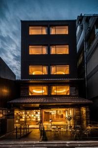 a black building with tables and chairs in front of it at Kyoto Shijo Takakura Hotel Grandereverie in Kyoto