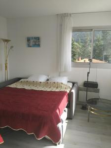 a bedroom with a bed with a red blanket and a window at la Catalane in Vernet-les-Bains