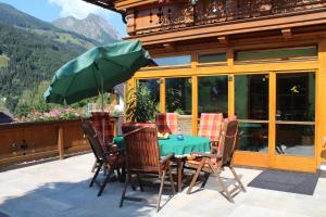 stół z krzesłami i parasol na patio w obiekcie Gästehaus ALPINA w mieście Dorfgastein