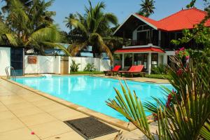 a swimming pool in front of a house with palm trees at Petit Elephant in Cherai Beach