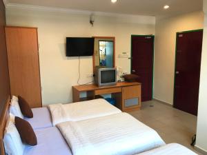 a hotel room with two beds and a television at Kangsar Hotel in Kuala Kangsar