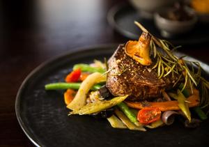 a black plate of food with meat and vegetables at Der Grüne Baum in Sinsheim