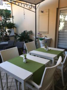 un patio con 2 tavoli e sedie con panna verde di B&B Borgo Marina a Bordighera