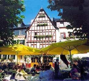 a group of people sitting under umbrellas in front of a building at Mosel-Landhaus Hotel Oster in Ediger-Eller