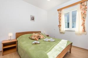 a bedroom with a bed with a green blanket and a window at Villas Rab Palit in Rab
