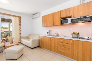 a kitchen with wooden cabinets and a living room at Villas Rab Palit in Rab