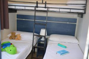2 letti a castello con orsacchiotti e un libro di Happy Camp mobile homes in Camping Villaggio Internazionale a San Menaio