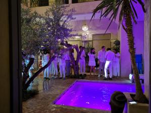 grupa ludzi stojących wokół basenu z fioletowymi światłami w obiekcie Riad Vendôme & Spa w Marakeszu