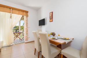 a dining room with a table and chairs and a television at Villas Rab Palit in Rab