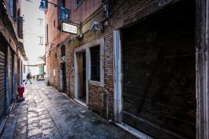 an alley in an old building with a person walking down it at Hotel Guerrato in Venice