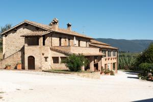 a large stone building with a road in front of it at Farm stay Il Carro del Colle in Collevalenza