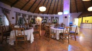 a dining room with white tables and chairs and chandeliers at African Rest Lodge in Barberton