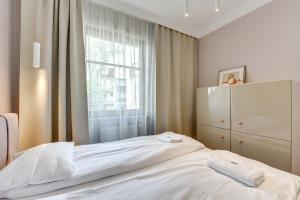 1 dormitorio con cama blanca y ventana en Sopocka Bryza - Baltica Apartments, en Sopot