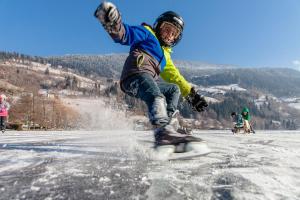 mężczyzna jeżdżący na snowboardzie po śniegu pokrytym stoku w obiekcie Rosie | Design | Chalet w mieście Bad Kleinkirchheim