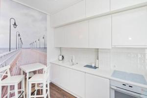 a white kitchen with white cabinets and a balcony at YOURAPART Sopot Centrum Plaza in Sopot