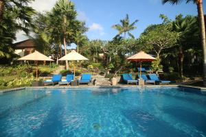 a swimming pool with blue chairs and umbrellas at Villa Capung Mas Ubud in Ubud