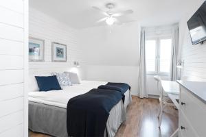 1 dormitorio blanco con 1 cama y ventilador de techo en Hotell Stenugnen, en Visby