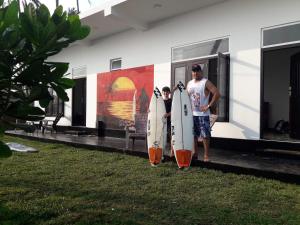 2 persone che tengono tavole da surf di fronte a un edificio di Sunset Surfing Beach Resort a Matara
