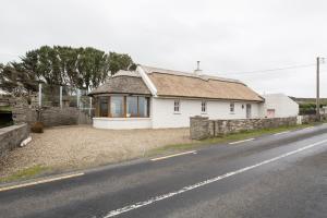 een wit huis aan de kant van een weg bij Storytellers Cottage in Upper Ballycotteen