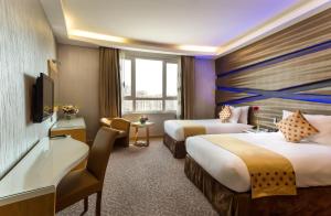 a hotel room with two beds and a television at Al Safir Hotel in Manama