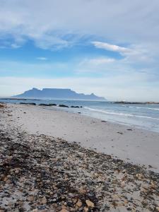 a beach with rocks and the ocean with a mountain at 180 Eden on the Bay, Big Bay in Big Bay