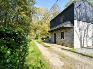 a stone house with a black roof and a dirt road at Charming gite in Les Avins situated by a stream in Modave