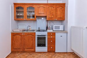 エゲルにあるArany Csillag Apartmanのキッチン(木製キャビネット、白いコンロ付)