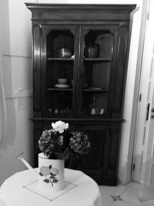 a black and white photo of a cabinet with flowers on a table at Palazzo Morese Apartments in Salerno