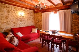 sala de estar con sofá rojo y mesa en El Refugi del Maestrat A - Turistrat, en Cervera del Maestre