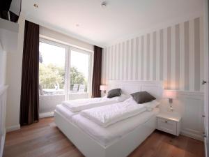 a white bedroom with a large bed and a window at Blanker Hans Wohnung 4 in Wangerooge