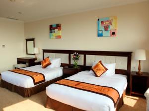 Habitación de hotel con 2 camas con almohadas de color naranja en Ha Long DC Hotel en Ha Long