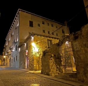 Un antiguo edificio de piedra con luces en una calle por la noche. en Hotel Convento Del Giraldo, en Cuenca