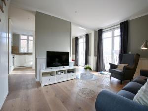 een woonkamer met een televisie, een bank en een tafel bij Charlotte 48 - Wunderschöne Ferienwohnung mit Balkon und Sauna in Wangerooge