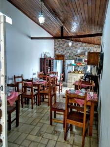 una sala da pranzo con tavoli e sedie in legno e una cucina di Pousada Sinhá Vilaça a Tiradentes